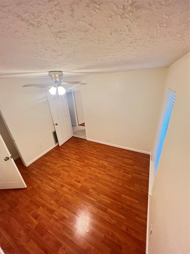 empty room with ceiling fan, hardwood / wood-style floors, and a textured ceiling