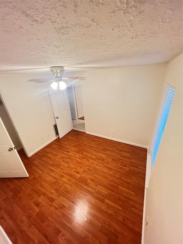 empty room with hardwood / wood-style flooring, ceiling fan, and a textured ceiling