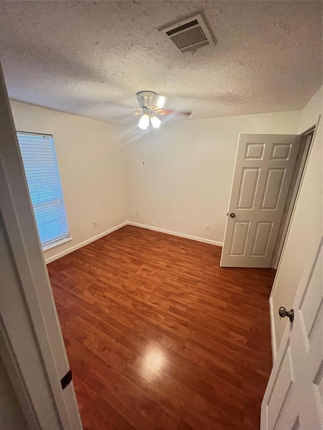 unfurnished bedroom featuring ceiling fan, dark hardwood / wood-style flooring, and a textured ceiling