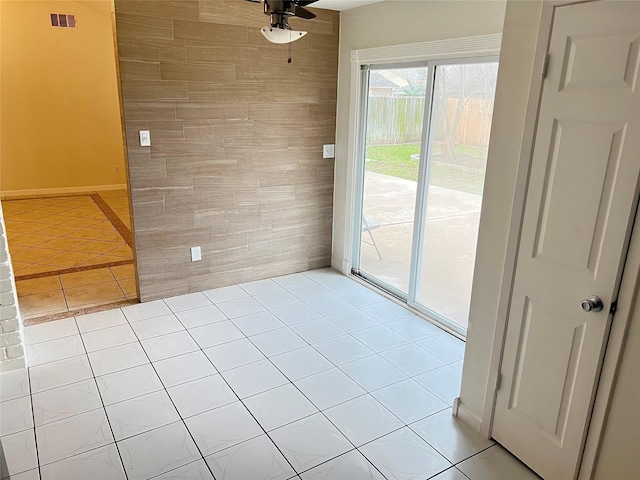 interior space featuring tile walls, light tile patterned floors, and ceiling fan