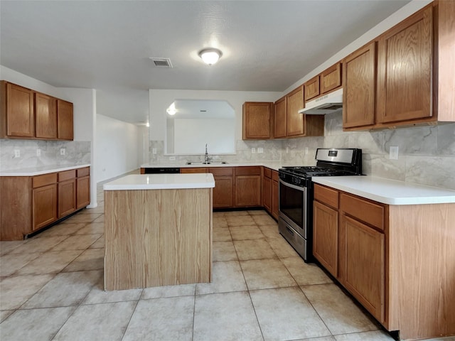 kitchen with sink, gas stove, a center island, light tile patterned floors, and decorative backsplash