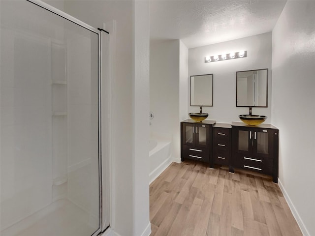 bathroom with hardwood / wood-style flooring, shower with separate bathtub, vanity, and a textured ceiling