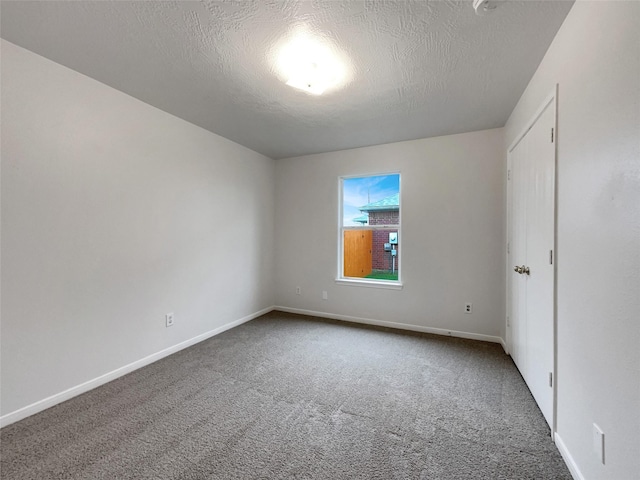 carpeted empty room with a textured ceiling