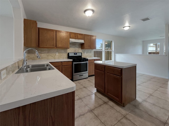 kitchen featuring stainless steel gas range oven, a center island, sink, and backsplash