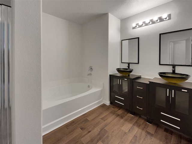 bathroom featuring a washtub, hardwood / wood-style floors, vanity, and a textured ceiling