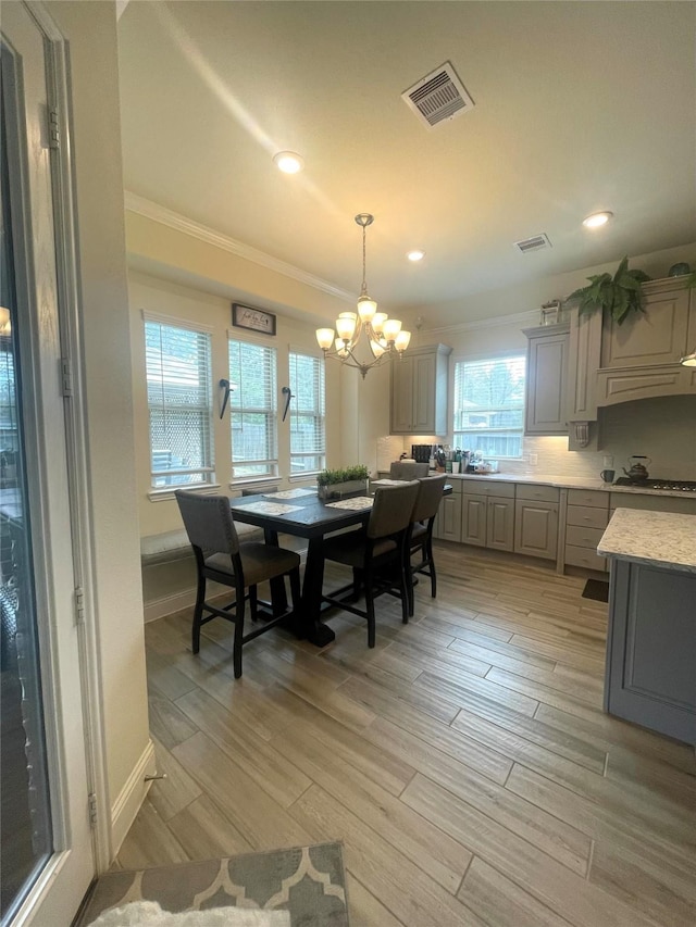 dining room featuring ornamental molding, a notable chandelier, and light hardwood / wood-style flooring