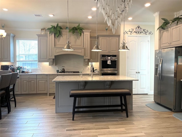 kitchen with light stone counters, gray cabinets, stainless steel appliances, and a center island with sink