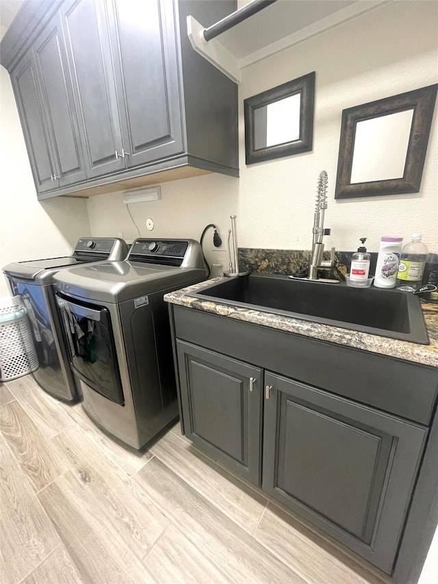 laundry room featuring sink, washing machine and dryer, and cabinets