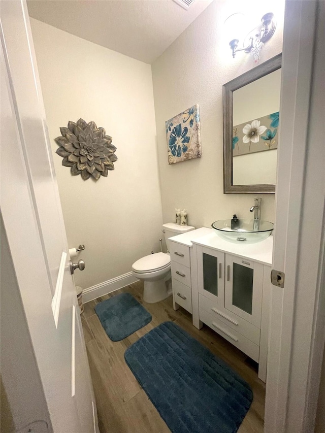 bathroom with wood-type flooring, toilet, and vanity