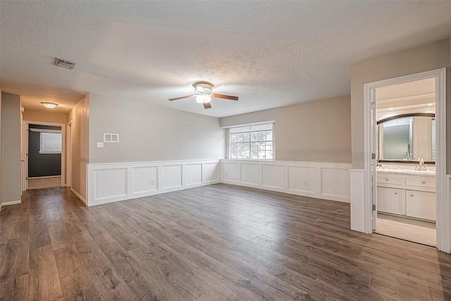 unfurnished room with ceiling fan, dark hardwood / wood-style floors, sink, and a textured ceiling