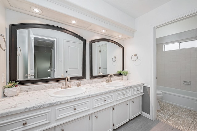 full bathroom with tiled shower / bath, vanity, and toilet