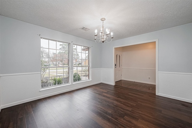 spare room with dark hardwood / wood-style flooring, a textured ceiling, and a chandelier