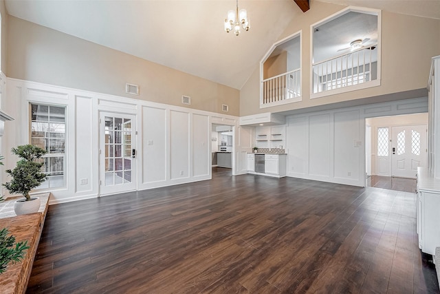 unfurnished living room featuring an inviting chandelier, high vaulted ceiling, and dark hardwood / wood-style floors