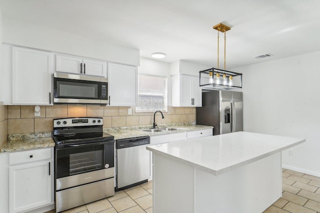 kitchen with a kitchen island, appliances with stainless steel finishes, pendant lighting, white cabinetry, and sink