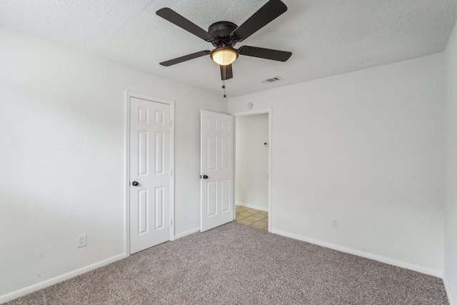 unfurnished bedroom featuring ceiling fan, light carpet, and a textured ceiling