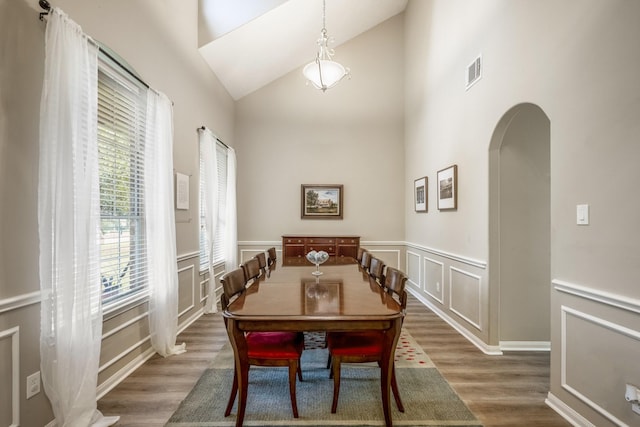 dining space with high vaulted ceiling and dark hardwood / wood-style flooring