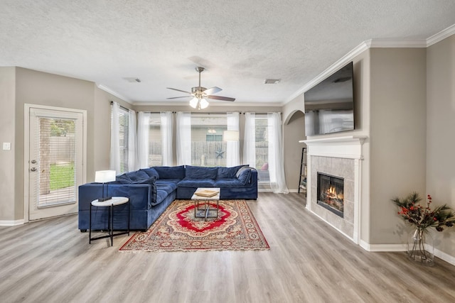 living room featuring a tile fireplace, ornamental molding, and light hardwood / wood-style floors