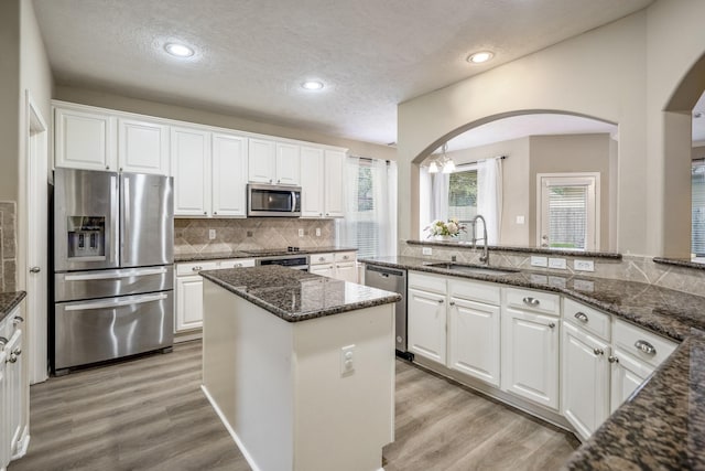 kitchen with white cabinetry, stainless steel appliances, sink, and dark stone counters