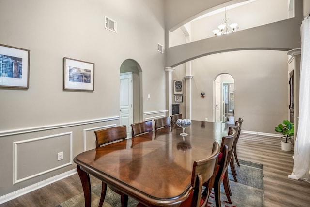 dining room with a high ceiling, dark wood-type flooring, and a chandelier