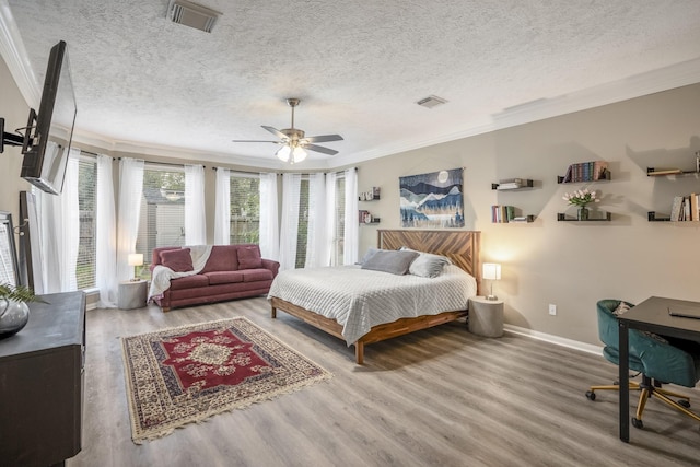 bedroom with ceiling fan, hardwood / wood-style flooring, ornamental molding, and a textured ceiling