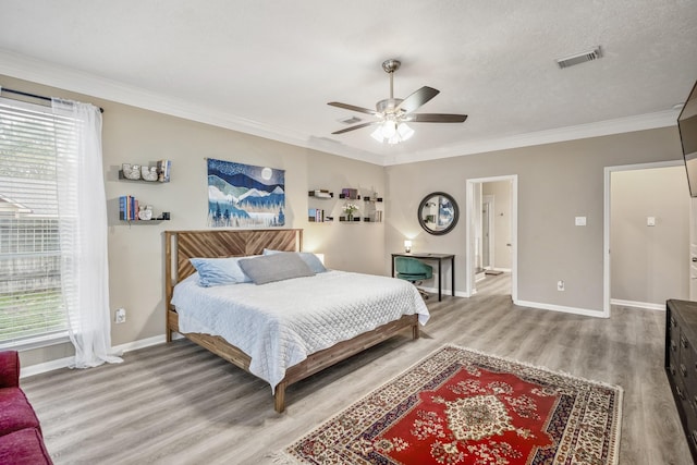 bedroom with hardwood / wood-style floors, crown molding, a textured ceiling, and ceiling fan