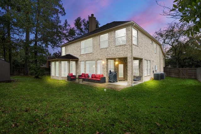 back house at dusk with an outdoor living space, a yard, central AC, and a patio area