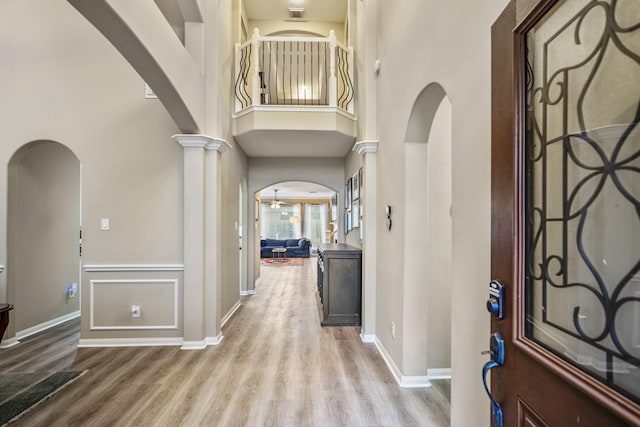 foyer featuring decorative columns, a high ceiling, and light wood-type flooring