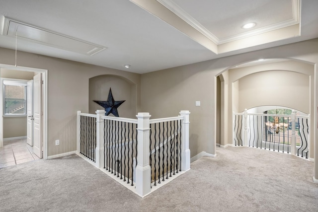 hallway featuring a raised ceiling, crown molding, and light carpet