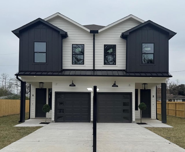 modern farmhouse with a standing seam roof, driveway, board and batten siding, and an attached garage