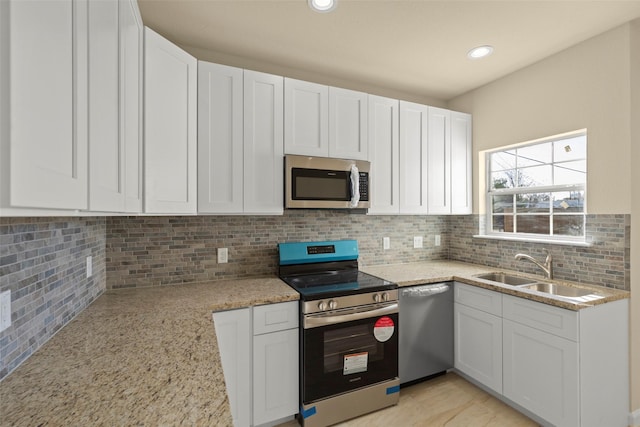 kitchen featuring stainless steel appliances, light stone countertops, sink, and white cabinets