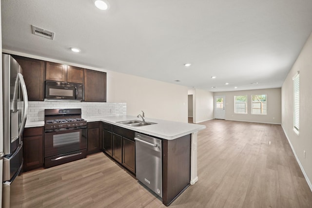 kitchen featuring black appliances, sink, backsplash, kitchen peninsula, and dark brown cabinets