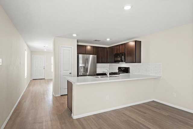 kitchen with light wood-type flooring, dark brown cabinetry, sink, and black appliances