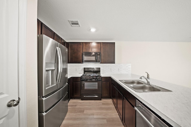 kitchen with sink, dark brown cabinets, black appliances, decorative backsplash, and light wood-type flooring