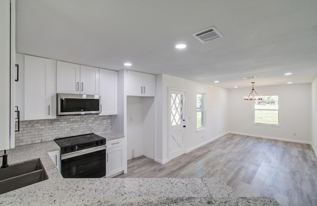 kitchen featuring decorative light fixtures, light stone countertops, backsplash, black electric range, and white cabinets