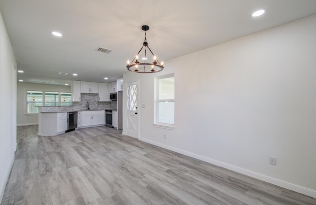 kitchen with appliances with stainless steel finishes, decorative light fixtures, decorative backsplash, sink, and white cabinetry