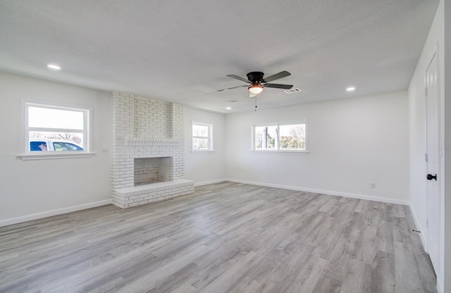 unfurnished living room featuring light hardwood / wood-style flooring, ceiling fan, a textured ceiling, and a fireplace