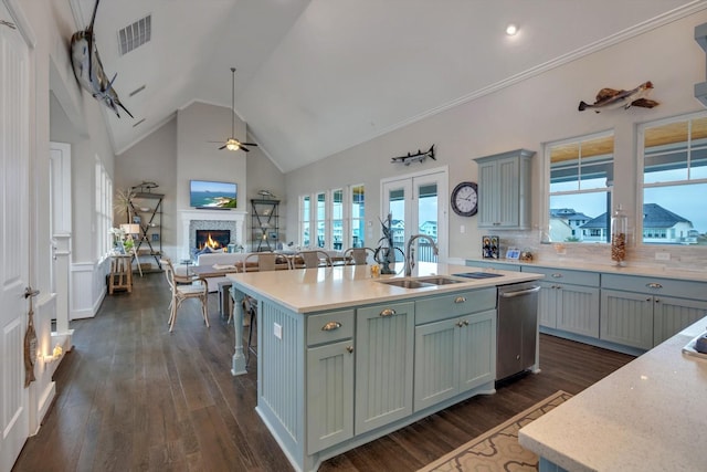 kitchen featuring an island with sink, sink, a kitchen breakfast bar, stainless steel dishwasher, and dark wood-type flooring
