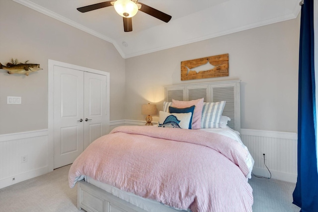 carpeted bedroom with ceiling fan, ornamental molding, vaulted ceiling, and a closet