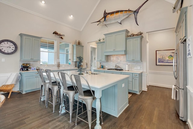 kitchen featuring dark wood-type flooring, stainless steel appliances, a kitchen breakfast bar, and a center island with sink