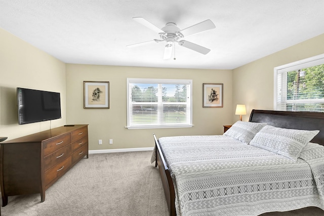 bedroom featuring multiple windows, light colored carpet, and ceiling fan