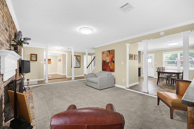 carpeted living room featuring crown molding, a fireplace, and decorative columns