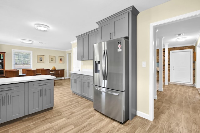 kitchen with gray cabinetry, stainless steel fridge with ice dispenser, ornamental molding, and light hardwood / wood-style floors