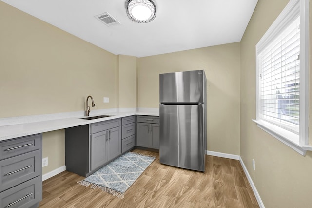 kitchen featuring light hardwood / wood-style flooring, sink, stainless steel fridge, and gray cabinets