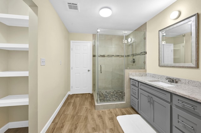 bathroom with wood-type flooring, a shower with door, and vanity