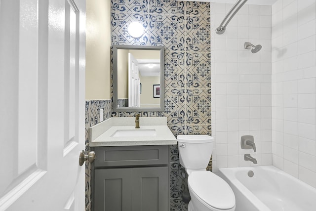 full bathroom featuring vanity, tiled shower / bath, and toilet