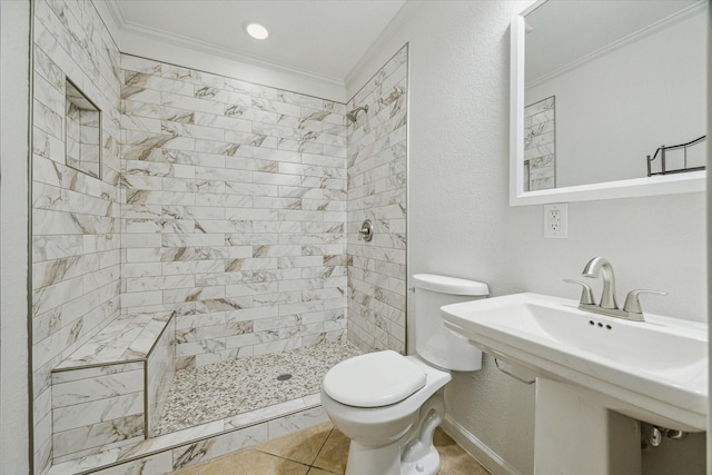 bathroom with a tile shower, sink, crown molding, and toilet