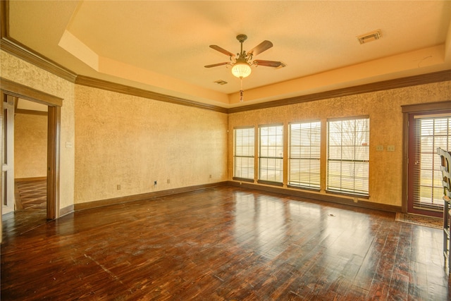 unfurnished room with dark wood-type flooring, ornamental molding, and a raised ceiling