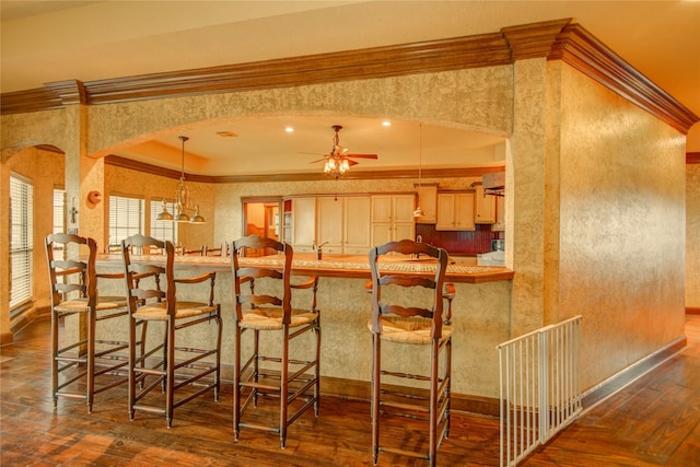 bar with wall chimney range hood, crown molding, dark wood-type flooring, ceiling fan, and decorative light fixtures