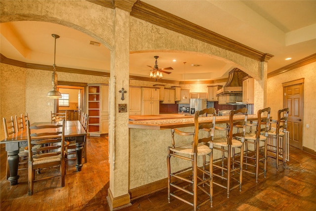 kitchen featuring dark hardwood / wood-style flooring, stainless steel fridge, kitchen peninsula, and light brown cabinets