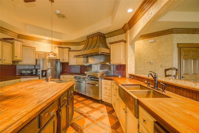 kitchen featuring appliances with stainless steel finishes, decorative light fixtures, butcher block countertops, and custom exhaust hood